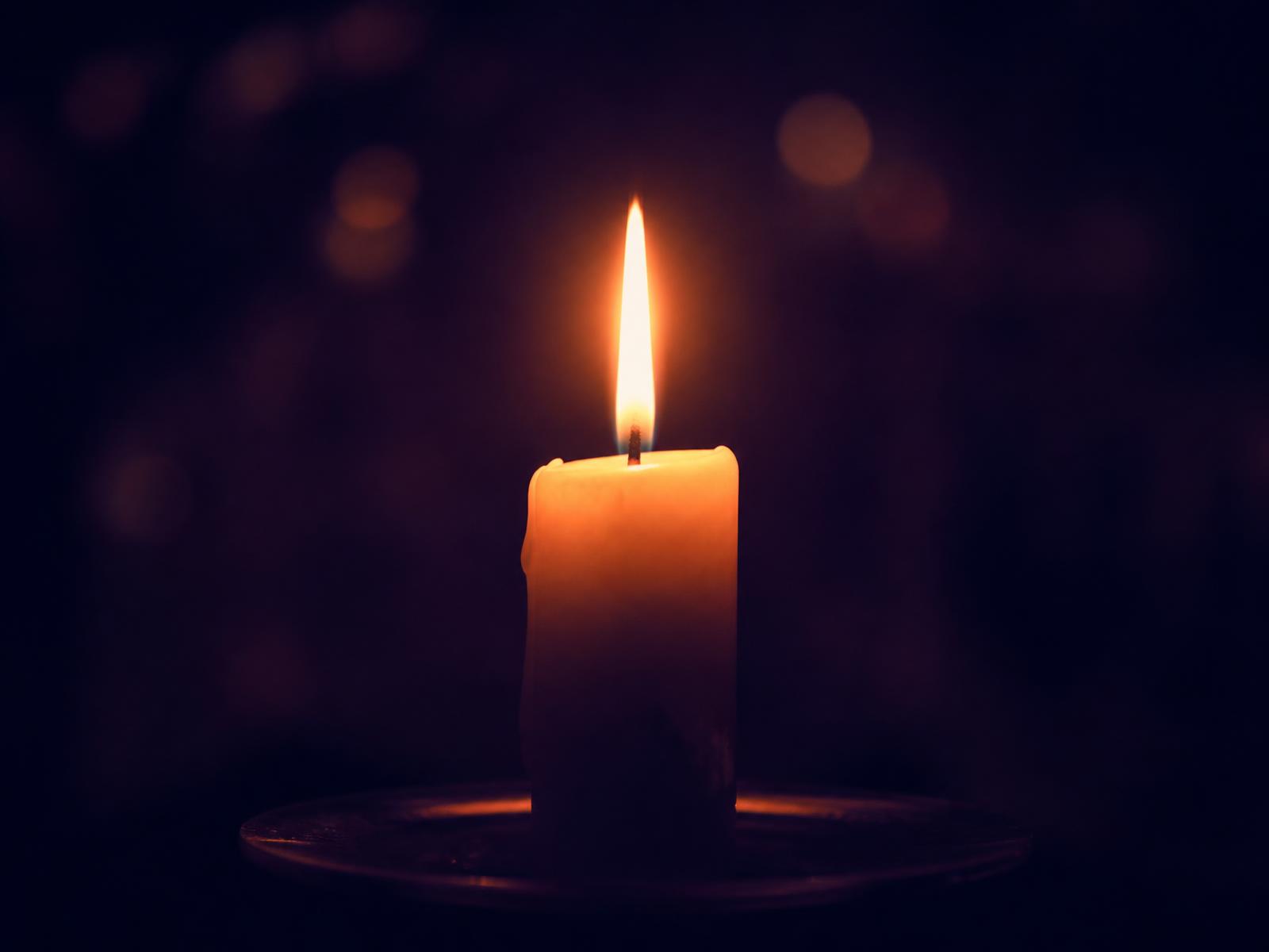 A single candle burning steadily in a darkened room