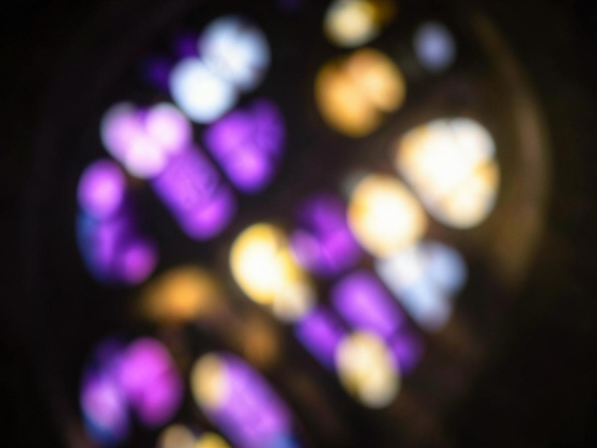 Abstract purple and gold light shining through a stained glass window, softly blurred